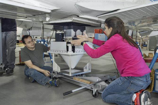 Engineers Raquel Rodriguez Monje and Fabien Nicaise discuss placement of the DopplerScatt radar instrument on the NASA B200 before its final installation onto the aircraft’s fuselage. Credits: NASA Photo / Ken Ulbrich