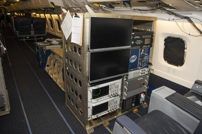 The High Altitude Lidar Observatory (HALO) system electronics and diagnostic tools are integrated onto the DC-8 airborne science laboratory at NASA Armstrong Flight Research Center in Edwards, California. The lidar system control electronics are on the right hand side of the rack. The large monitors on the left are used to display real-time images of water vapor and aerosol profiles, which are used by the science team to guide in-flight decisions and navigation. The compact HALO instrument head can be seen 