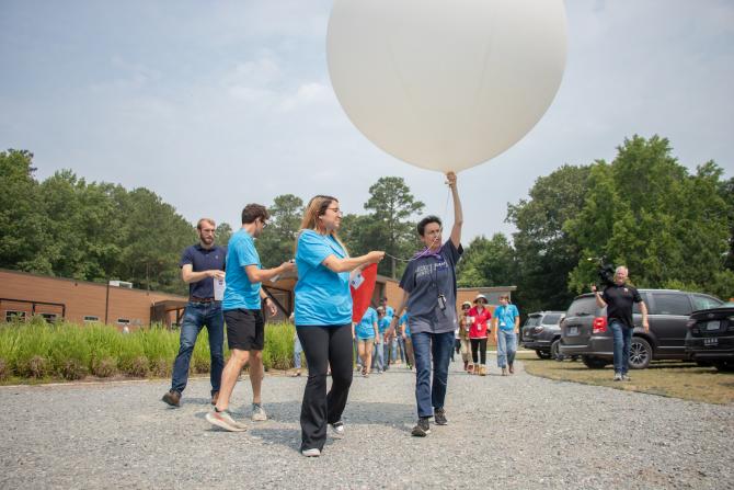 NASA SARP intern Karla Lemus, on left, assists NASA Scientist Emeritus Anne Thompson as she leads NASA SARP East interns, to release an ozone sonde from the parking lot of the VCU Rice Rivers Center on June 16, 2023. Credits: NASA/Angelique Herring
