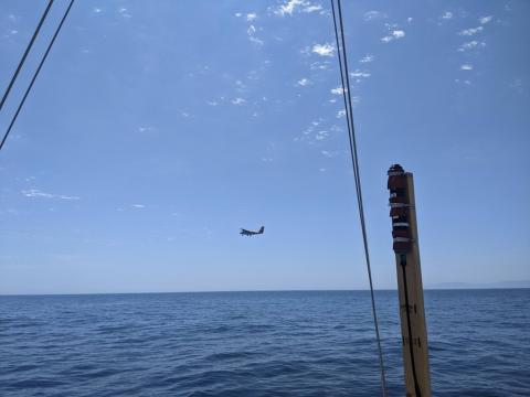 The Twin Otter research plane flies past RV Blissfully on sampling station. RV Blissfully’s surface light sensor is seen in the foreground. Photo by Bridget Seegers.